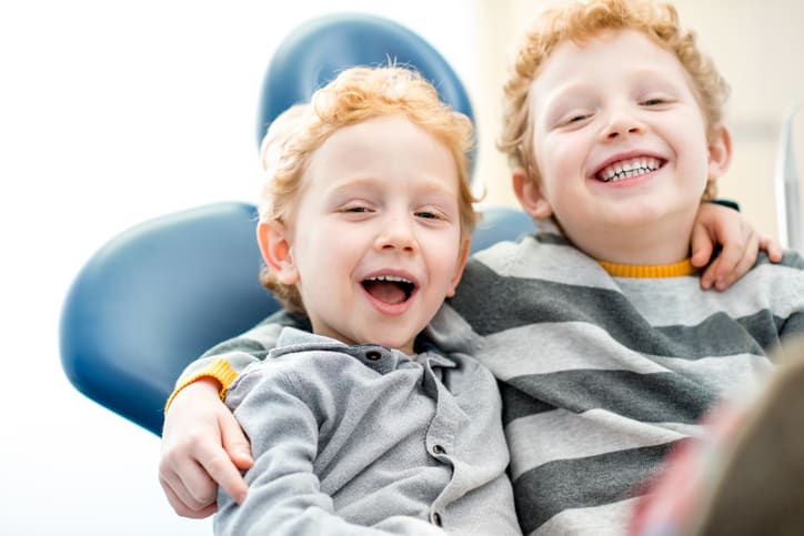 Portrait of a happy young brothers sitting on the dental chair at the dental office