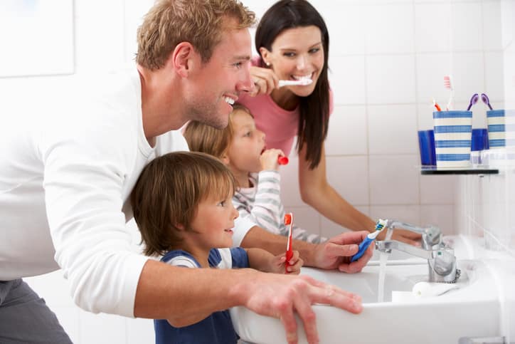 Family In Bathroom Brushing Teeth Together