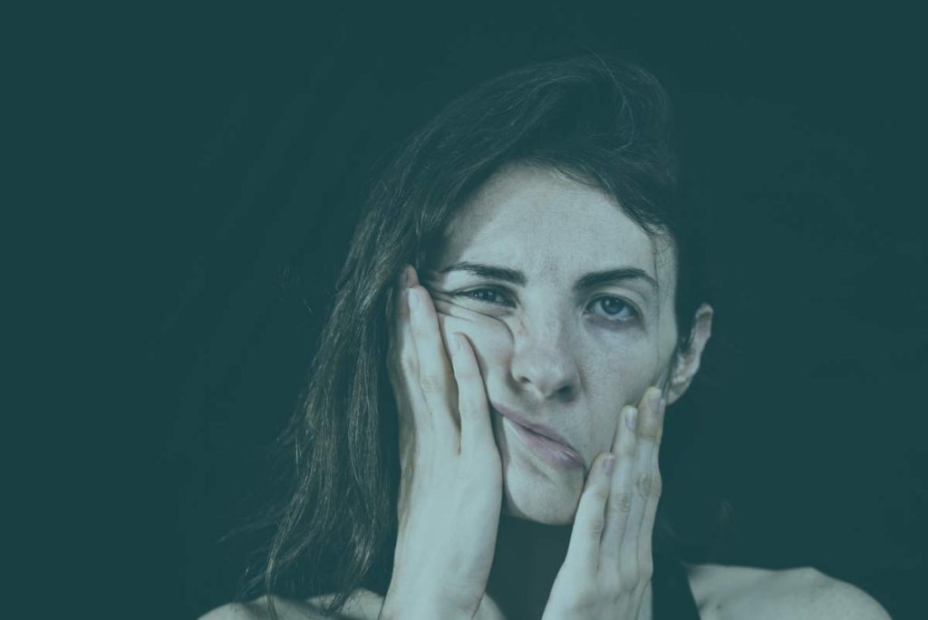 Woman holding her face in pain and frustration from the dental issue:bruxism